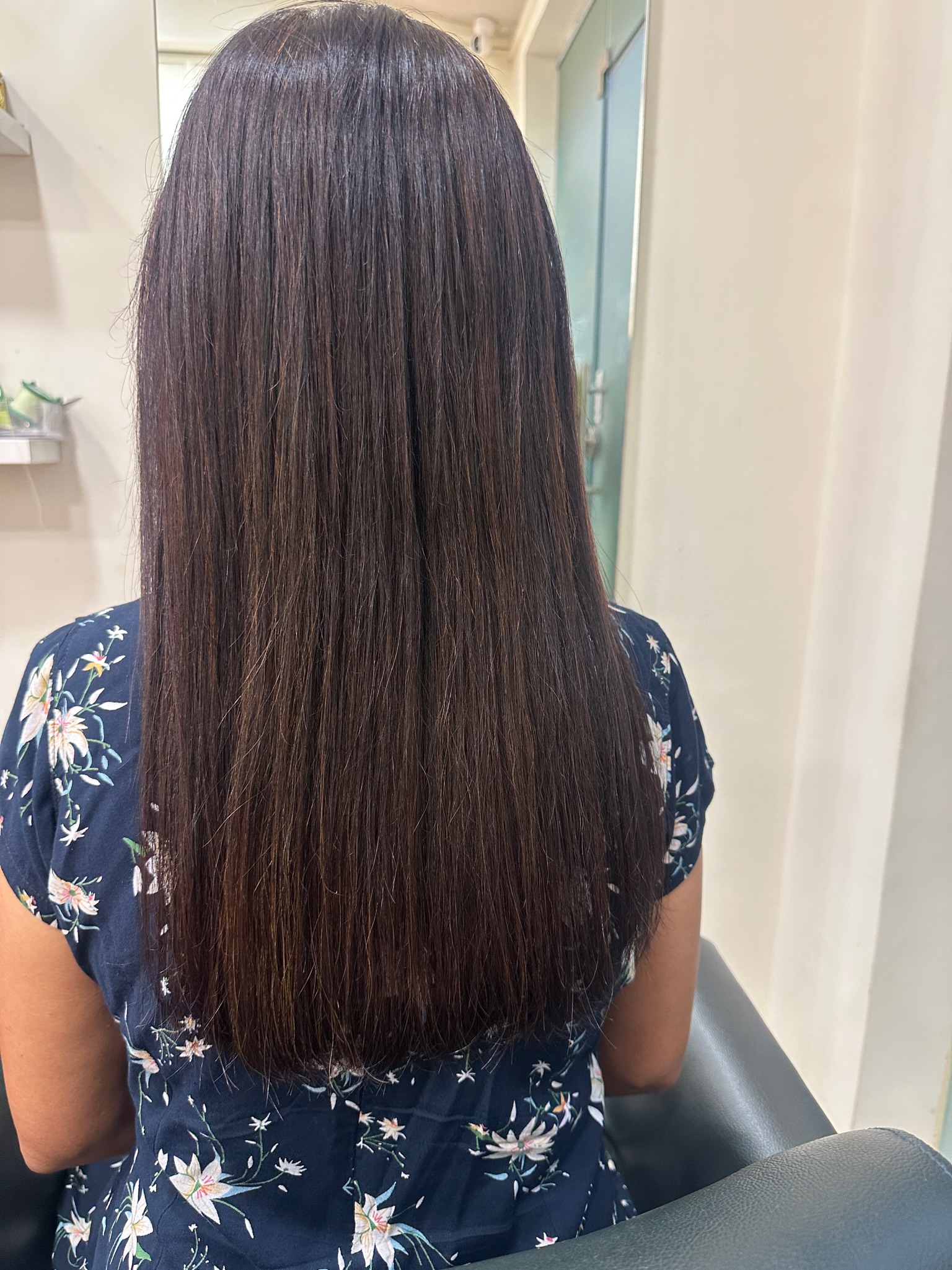 Back view of a woman with long, dark brown, visibly smooth, and shiny hair after a premium hair treatment at Seema's Hair & Skin Clinique.