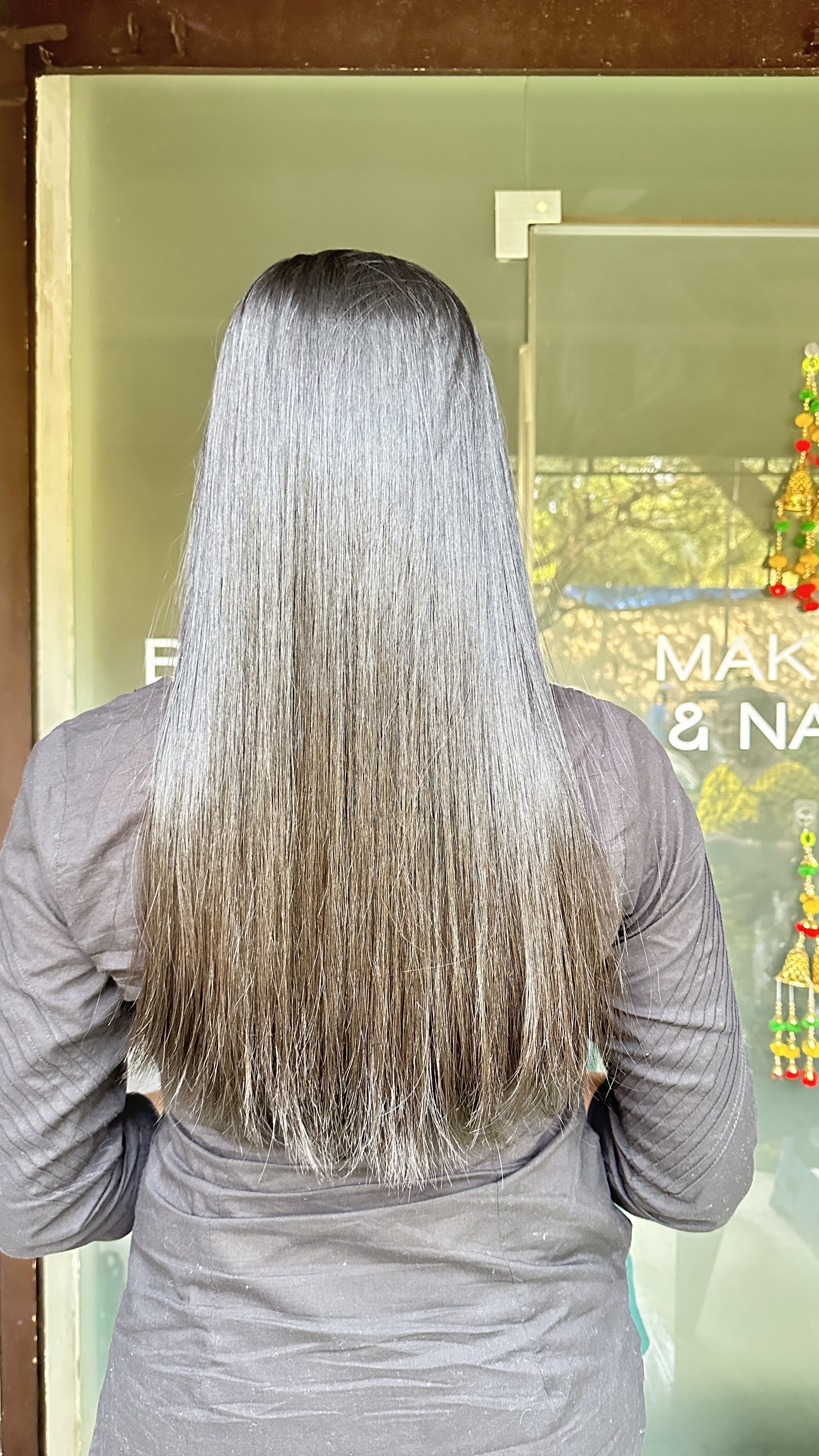 Post-Holiday Reset: Rejuvenate Your Skin & Hair After the Festive Rush in Borivali West, Mumbai 1 Rear view of a woman showcasing long, perfectly smooth, straight, and shiny hair with a subtle grey ombre effect, indicating a successful hair smoothening or advanced hair treatment at Seema's Hair & Skin Clinique in Borivali West, Mumbai.